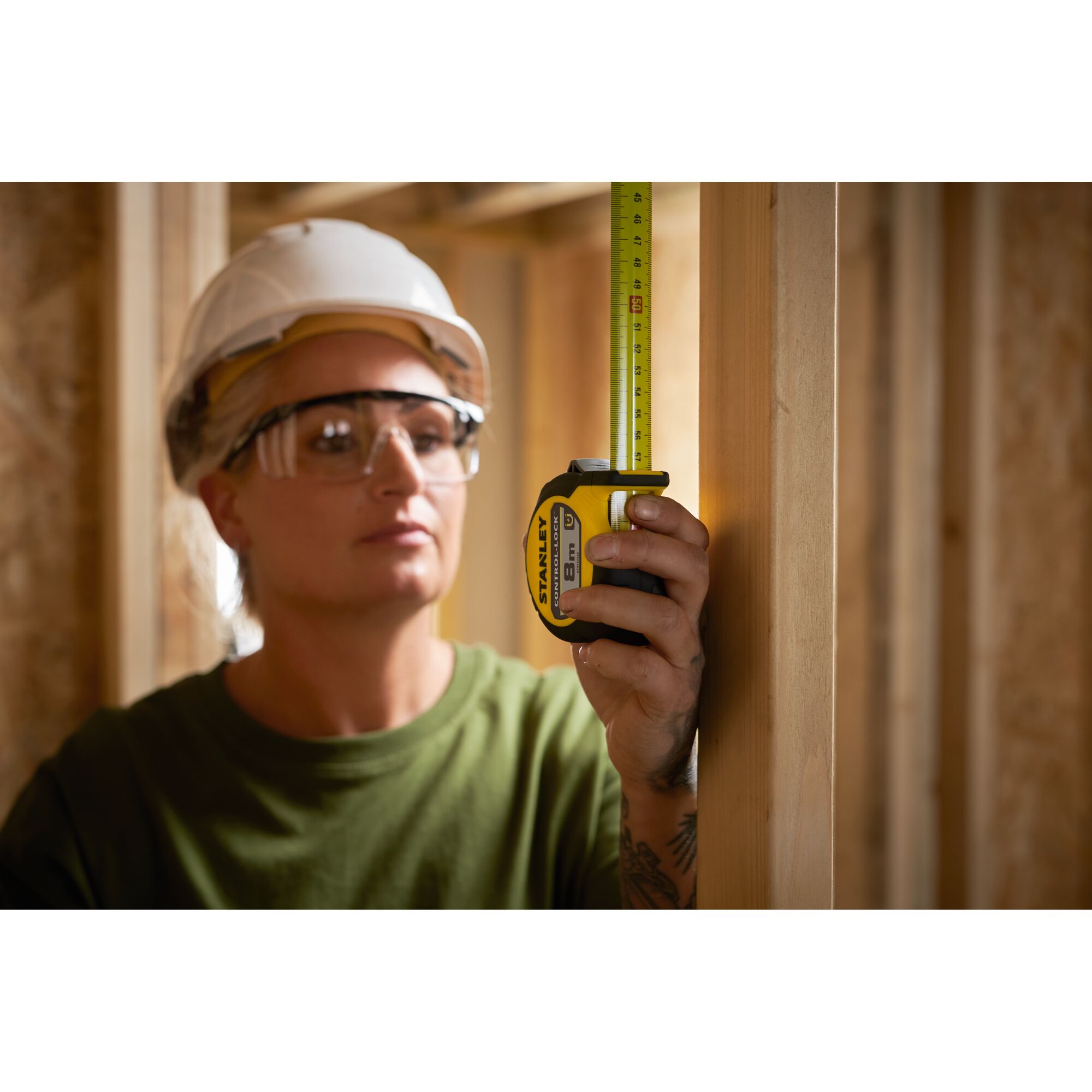 Photo of STANLEY STHT37232-0 tape measure in use, measuring wood frame at construction site.